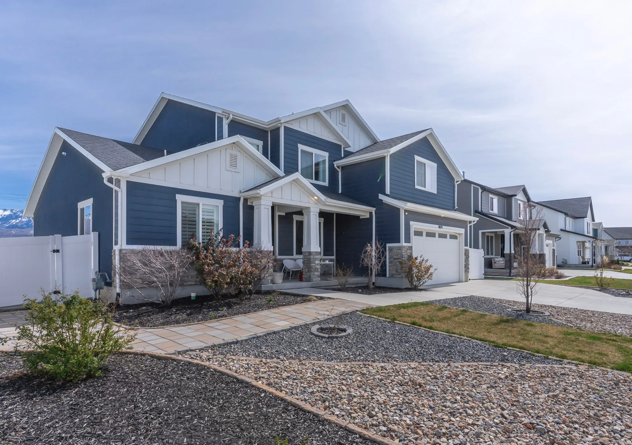 View of front of home featuring board and batten siding, driveway, a gate, a garage, and stone siding