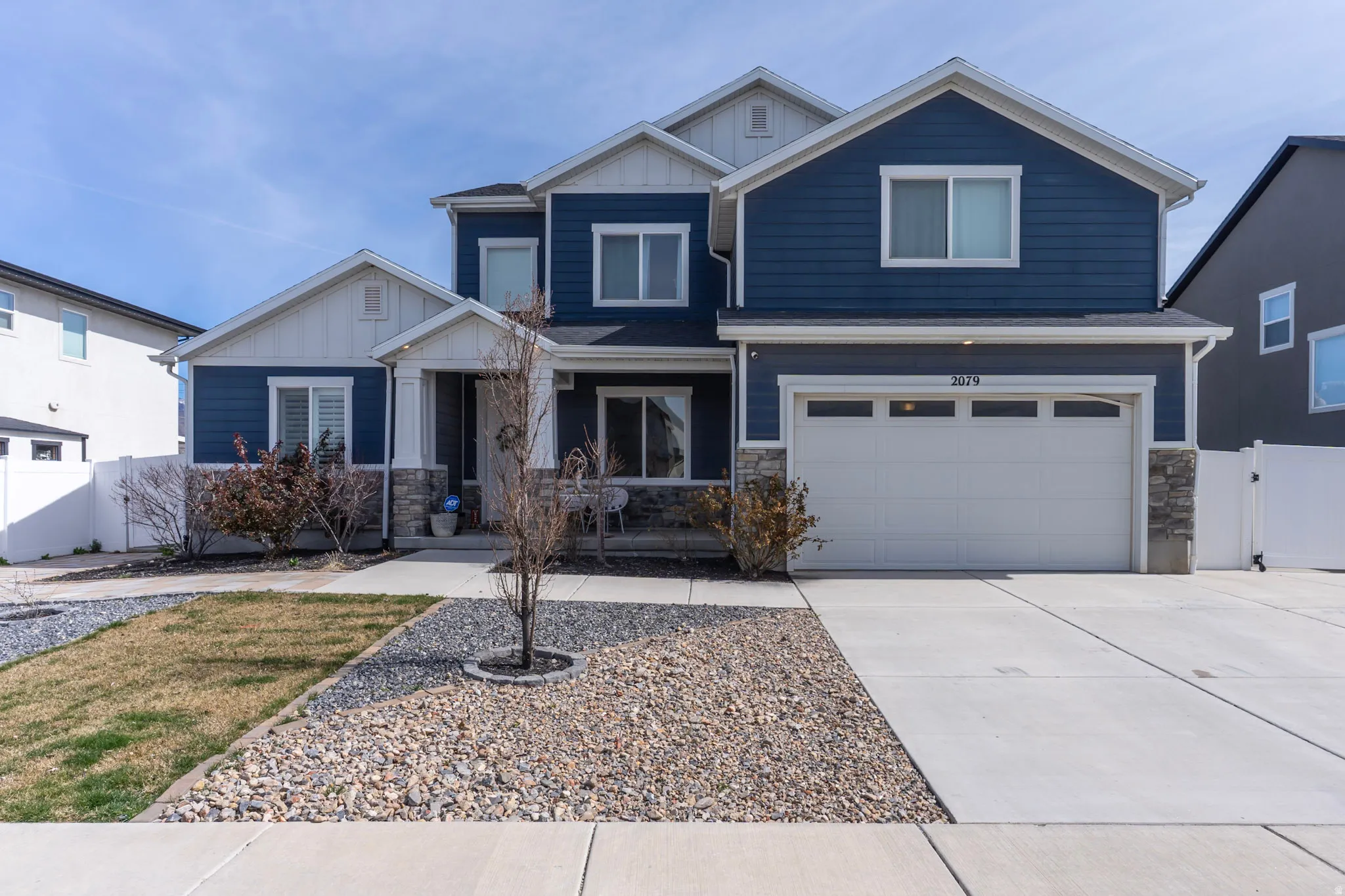 Craftsman house featuring stone siding, board and batten siding, a gate, a garage, and driveway