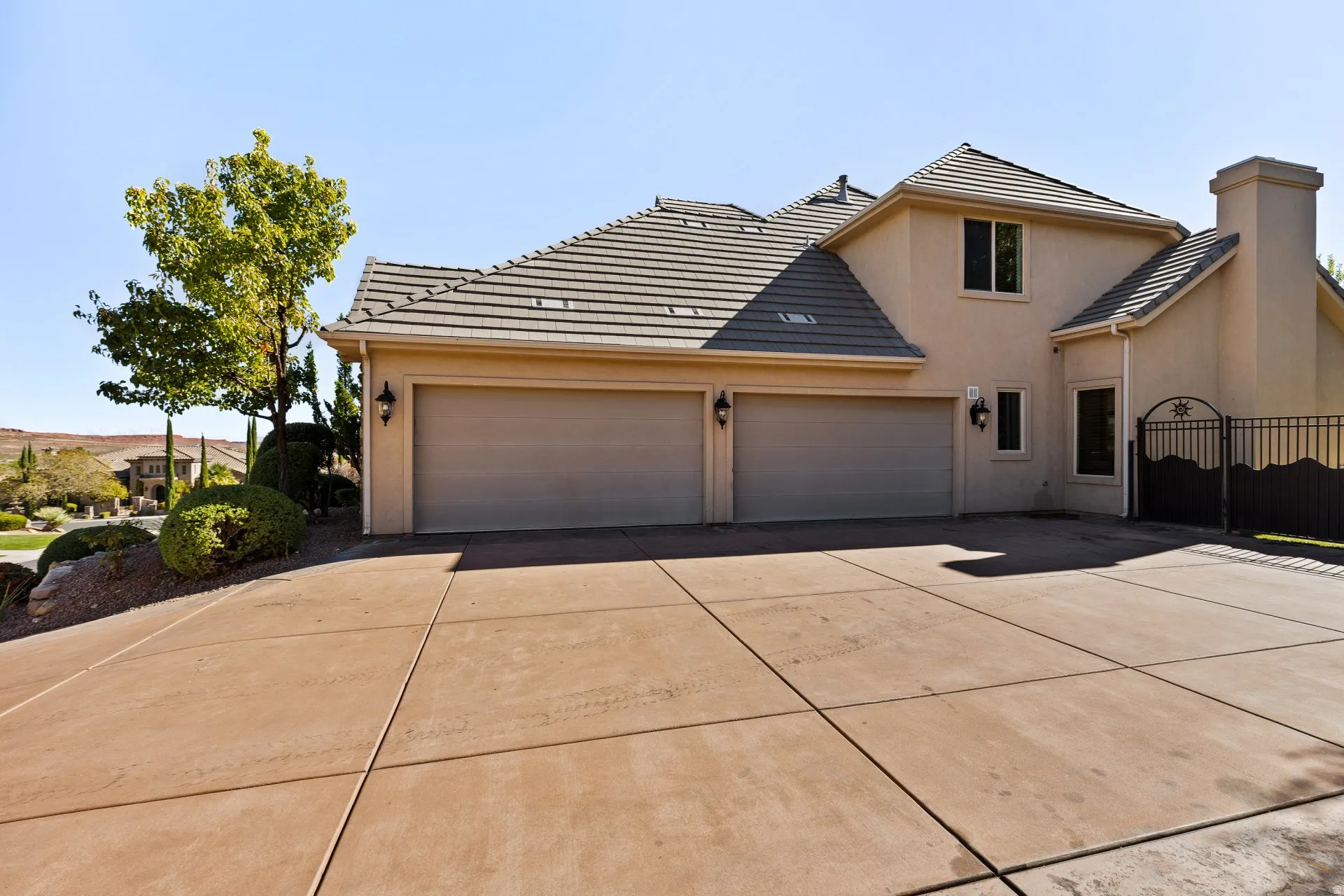 Traditional-style house with stucco siding, driveway, a chimney, an attached garage, and a tiled roof