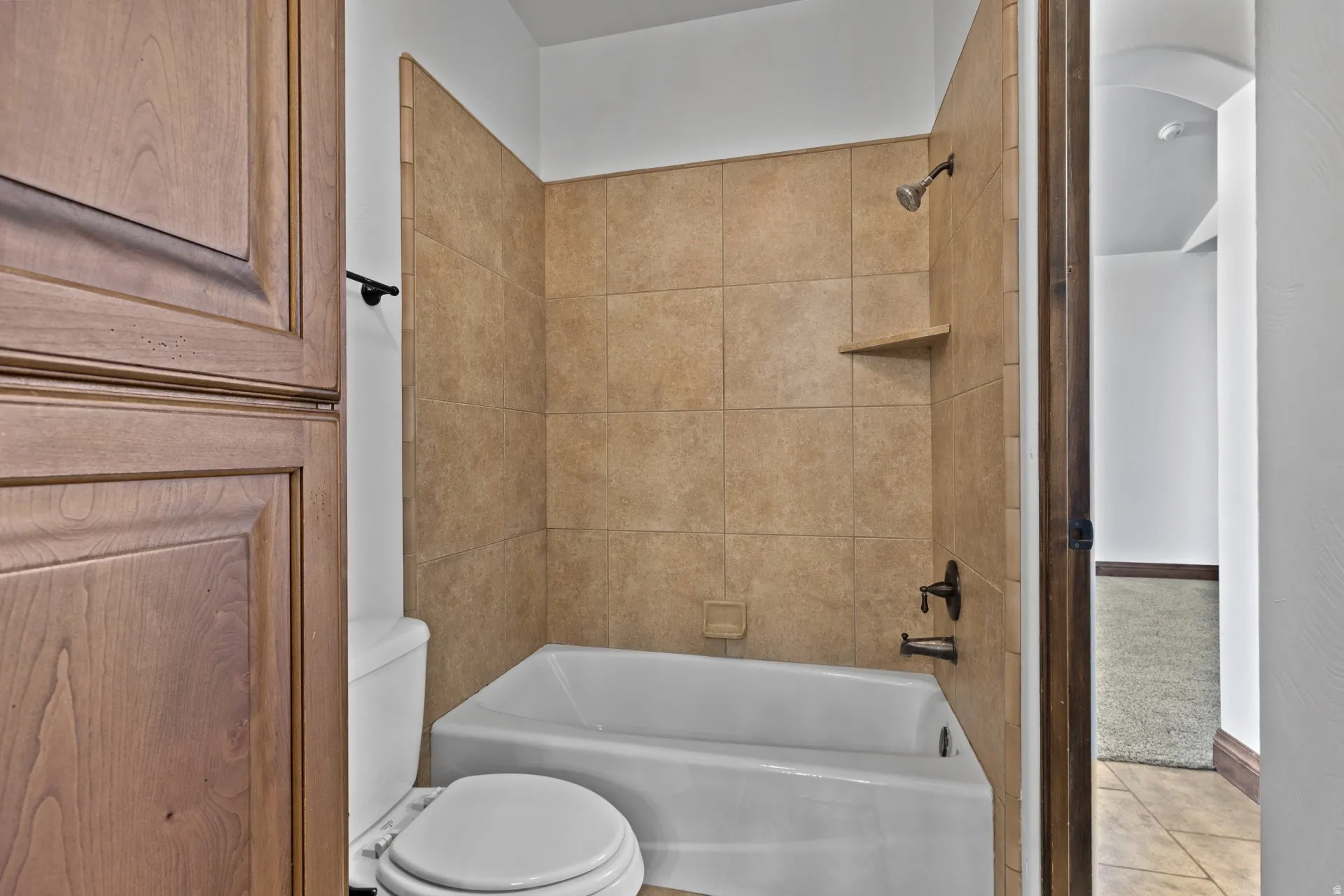 Bathroom with bathing tub / shower combination, tile patterned floors, and carpet