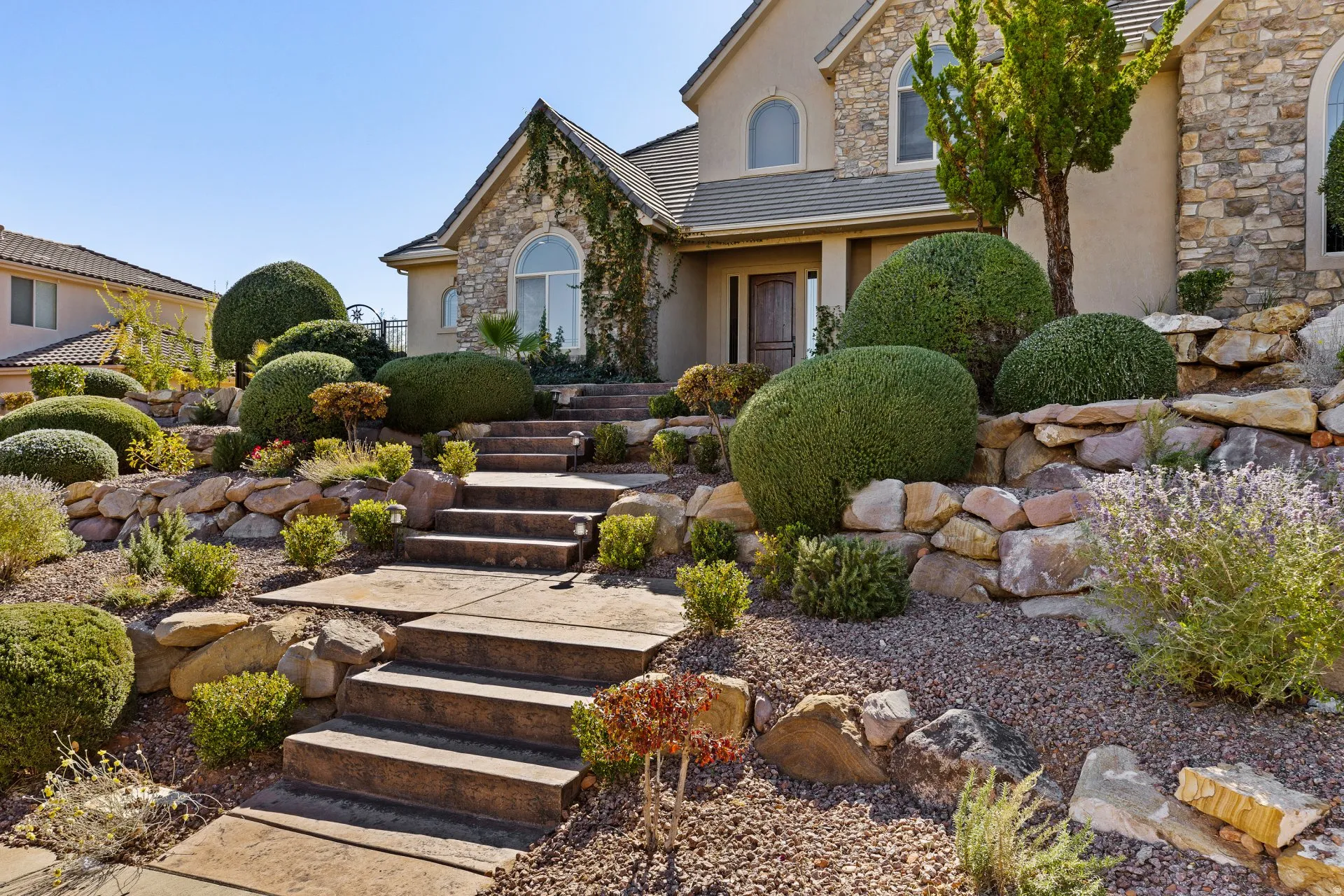 View of front of house featuring stone siding, stucco siding, and a tile roof