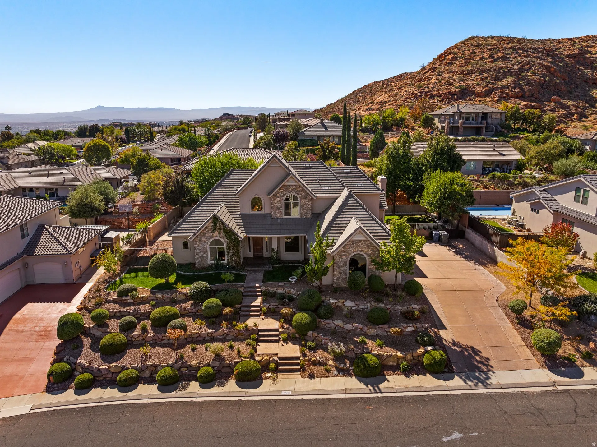 View of front of property featuring a residential view, stone siding, driveway, stucco siding, and a porch