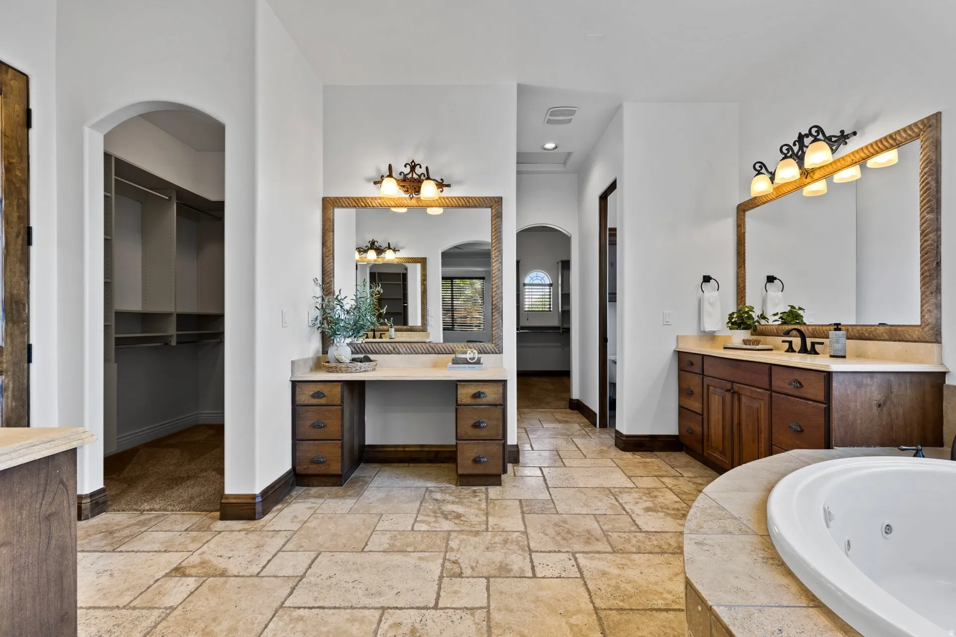 Full bath featuring a spacious closet, two vanities, stone tile floors, a whirlpool tub, and recessed lighting