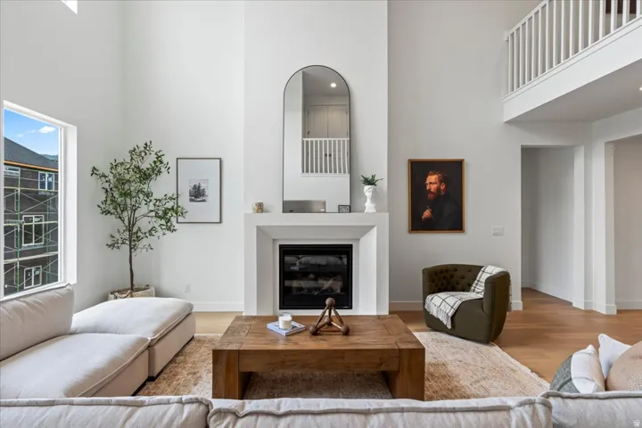 Living room featuring a high ceiling, a glass covered fireplace, and light wood finished floors