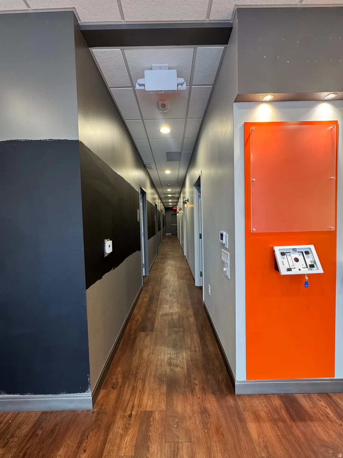 Hall with a paneled ceiling, dark wood-style floors, and recessed lighting