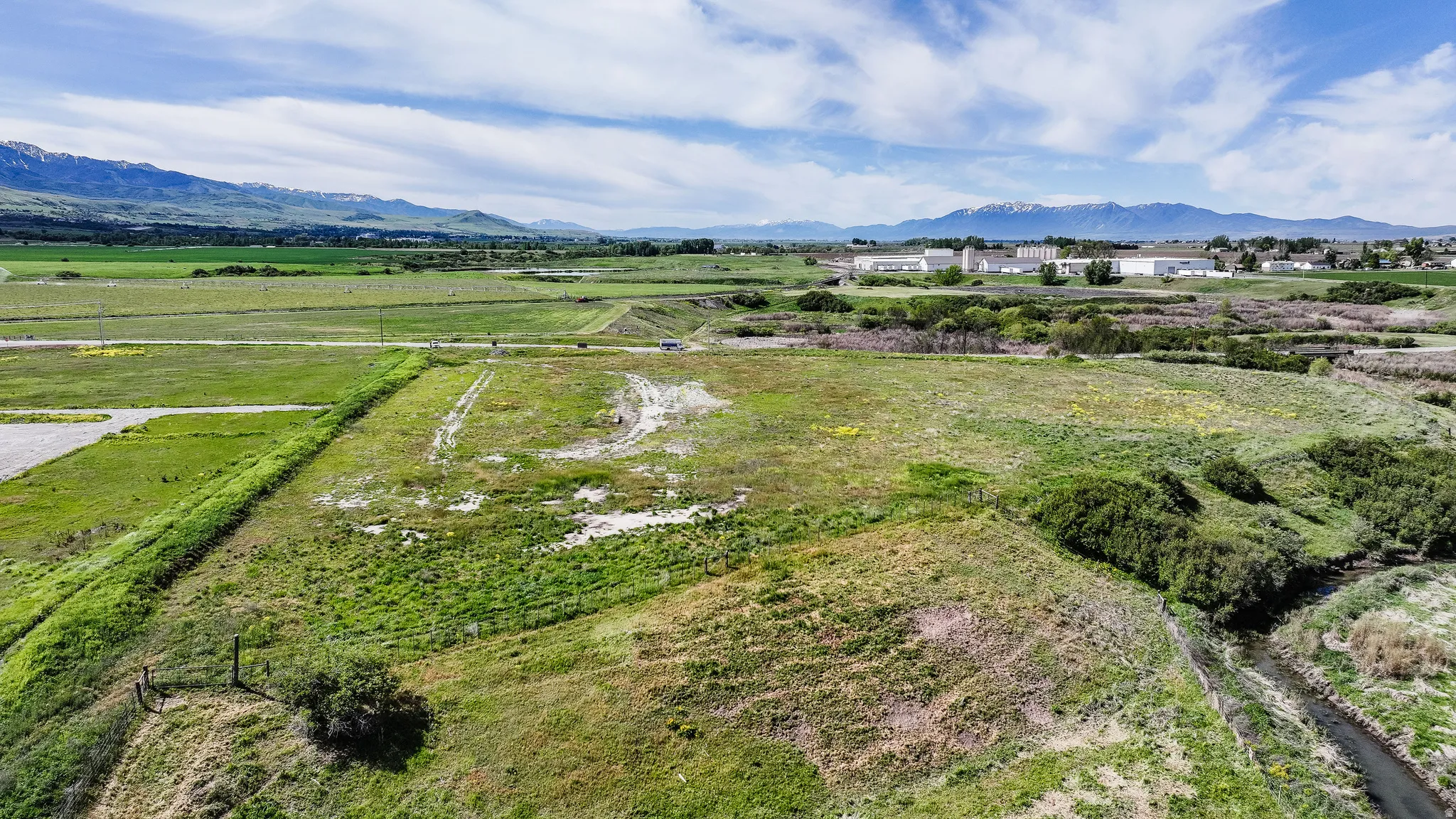 Expansive green landscape featuring varied terrain, a winding natural water feature, and distant mountain ranges