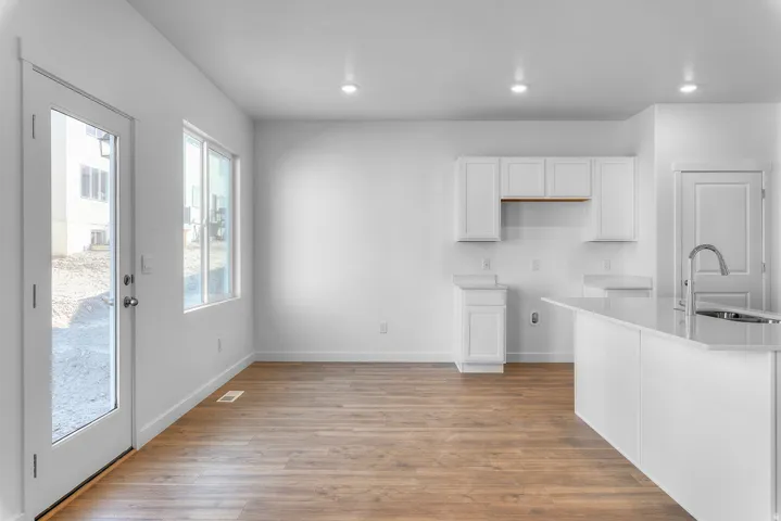 Kitchen with white cabinets, light wood finished floors, recessed lighting, and light stone countertops