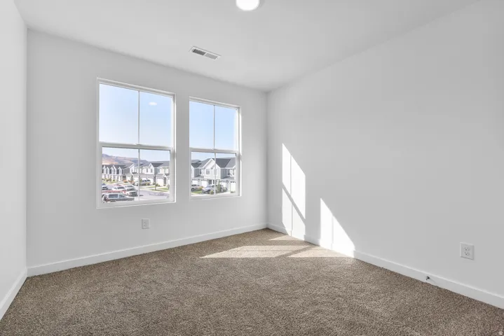 Carpeted empty room featuring baseboards and a residential view