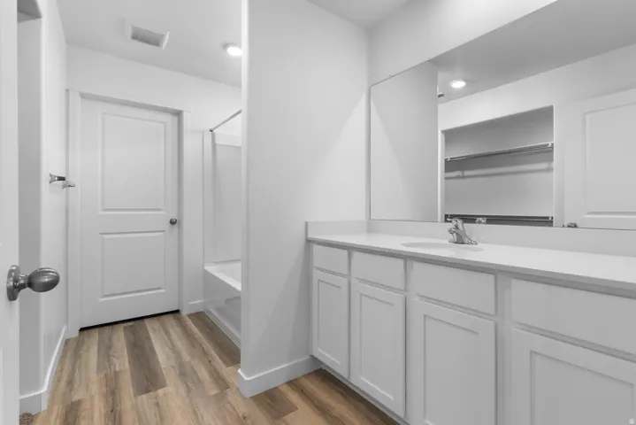 Bathroom featuring vanity, dark wood-style floors, shower / bath combination, and recessed lighting