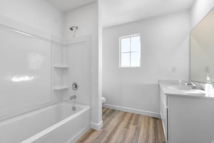 Full bathroom featuring vanity, washtub / shower combination, and dark wood-type flooring