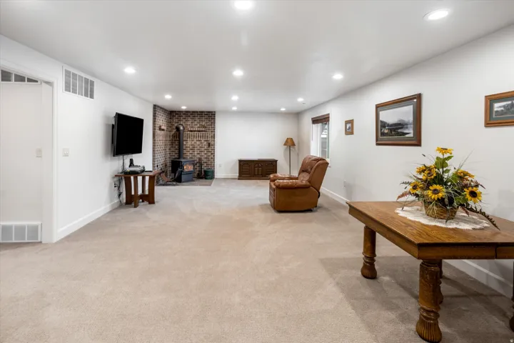 Living room with a wood stove, light carpet, and recessed lighting