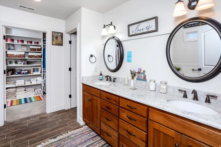 Bathroom with double vanity, wood finish floors, and a walk in closet