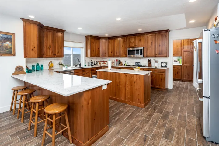Kitchen with wood finish cabinetry, wood finish floors, stainless steel appliances, and recessed lighting