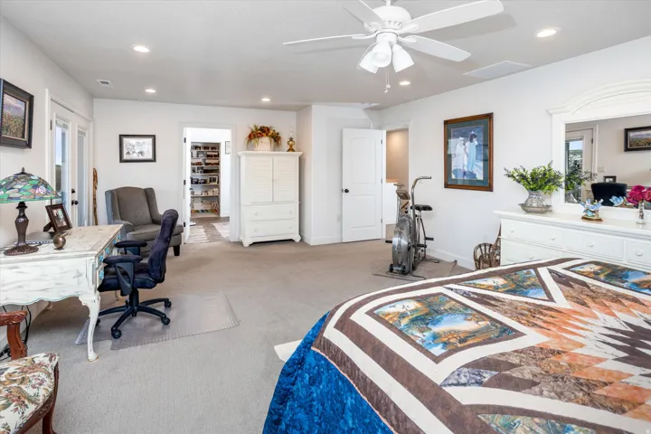 Bedroom with a spacious closet, carpet flooring, recessed lighting, ceiling fan, and an office area