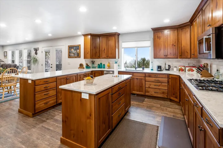 Kitchen featuring a peninsula, wood finish cabinetry, dark wood finished floors, french doors, and stainless steel appliances