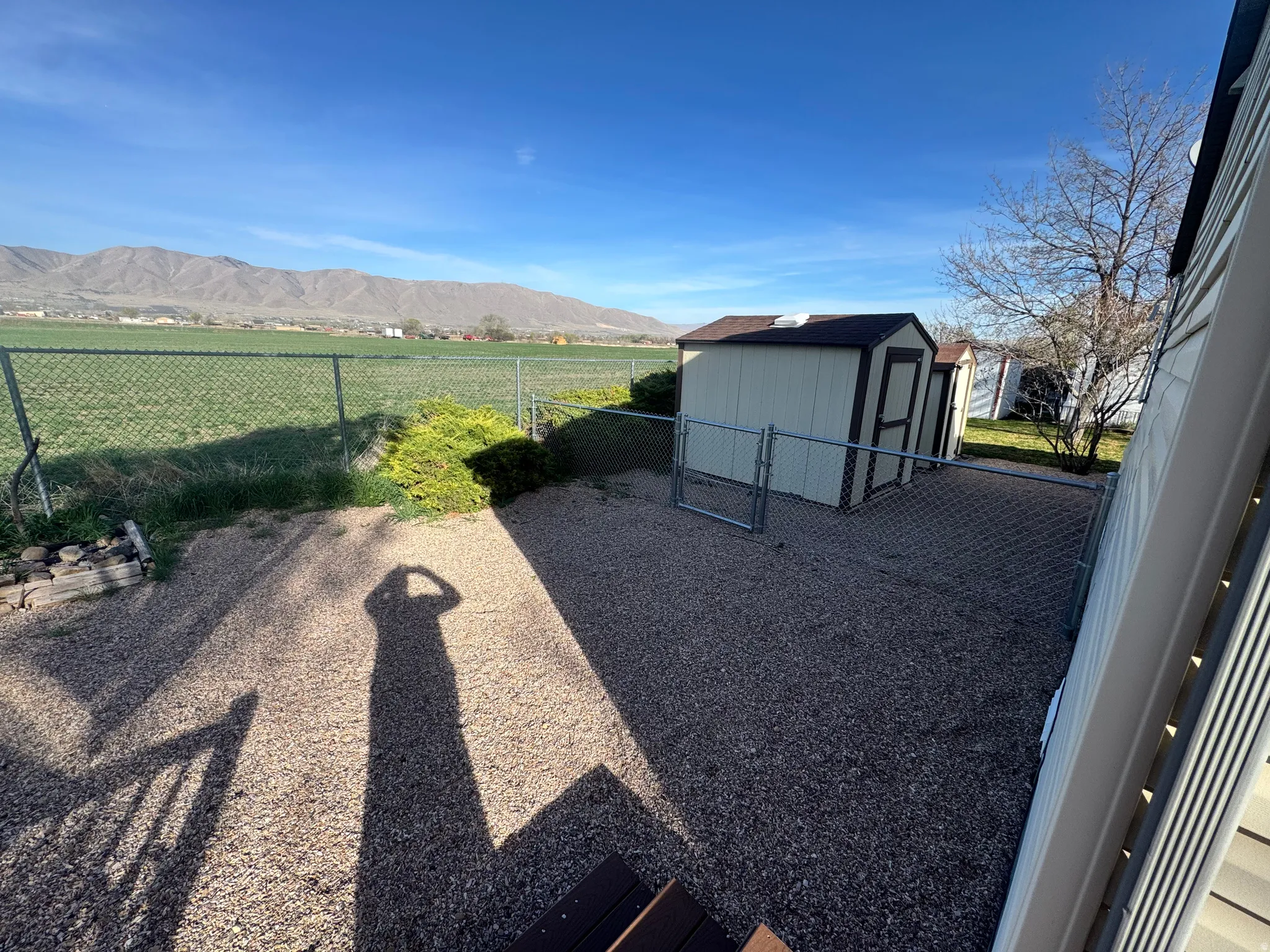 Fenced backyard featuring a mountain view, a storage unit, and a gate