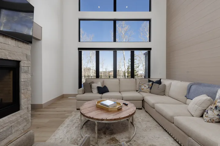 Living area with a fireplace, light wood-style floors, and a high ceiling