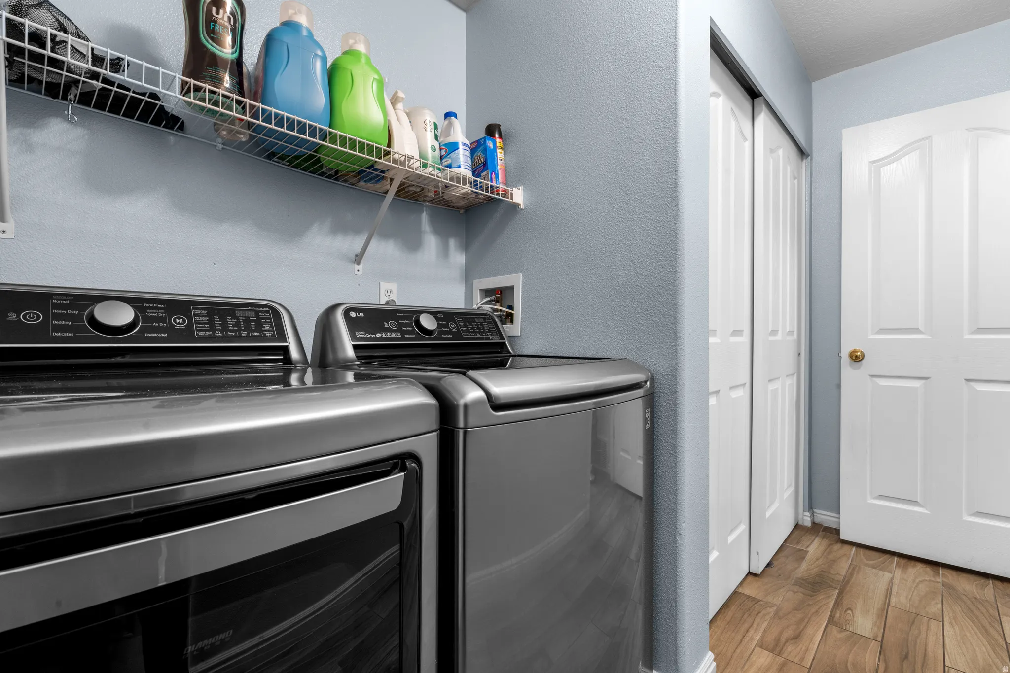 Laundry area featuring wood finished floors, a textured wall, and separate washer and dryer