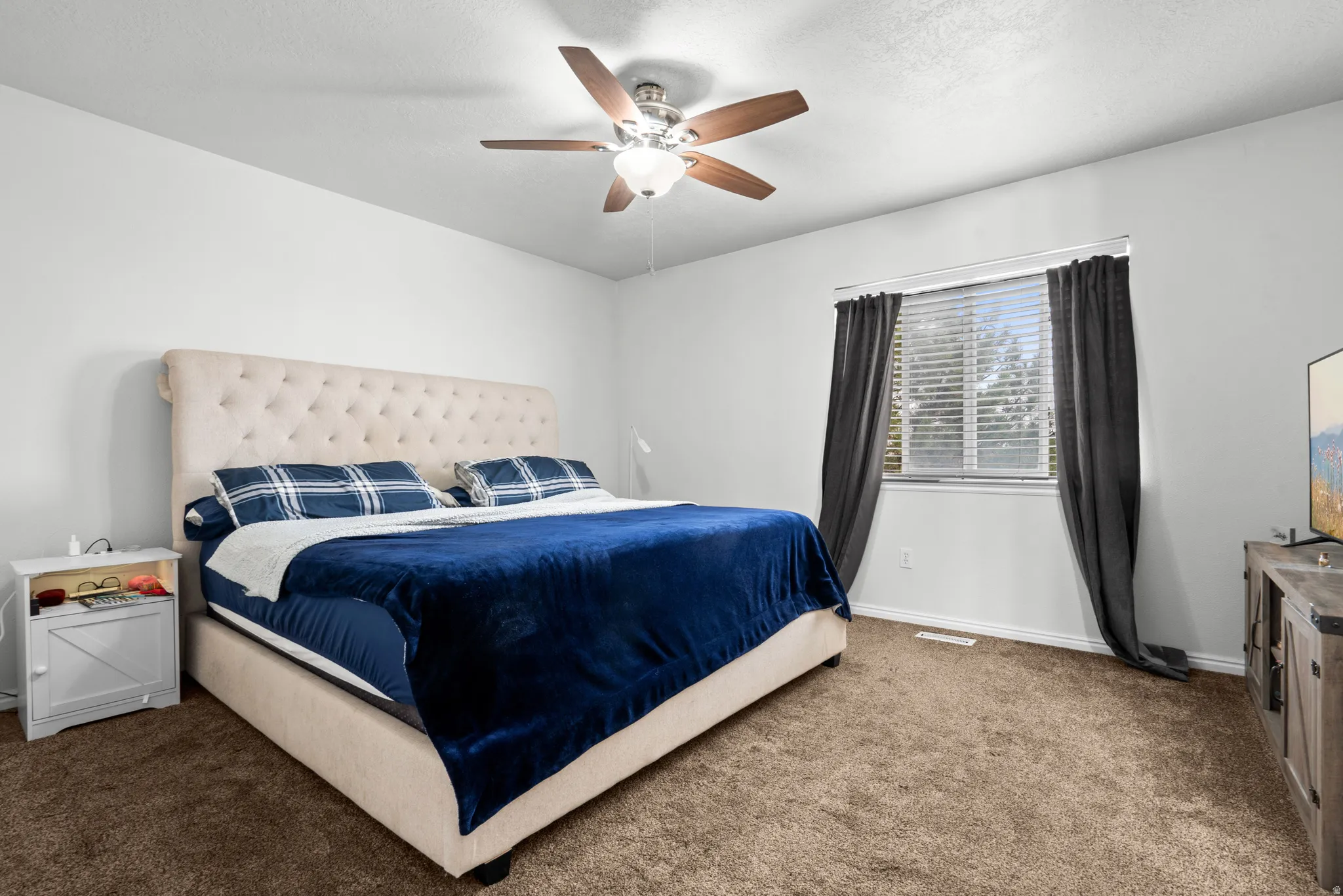 Bedroom featuring dark colored carpet, ceiling fan, and a textured ceiling