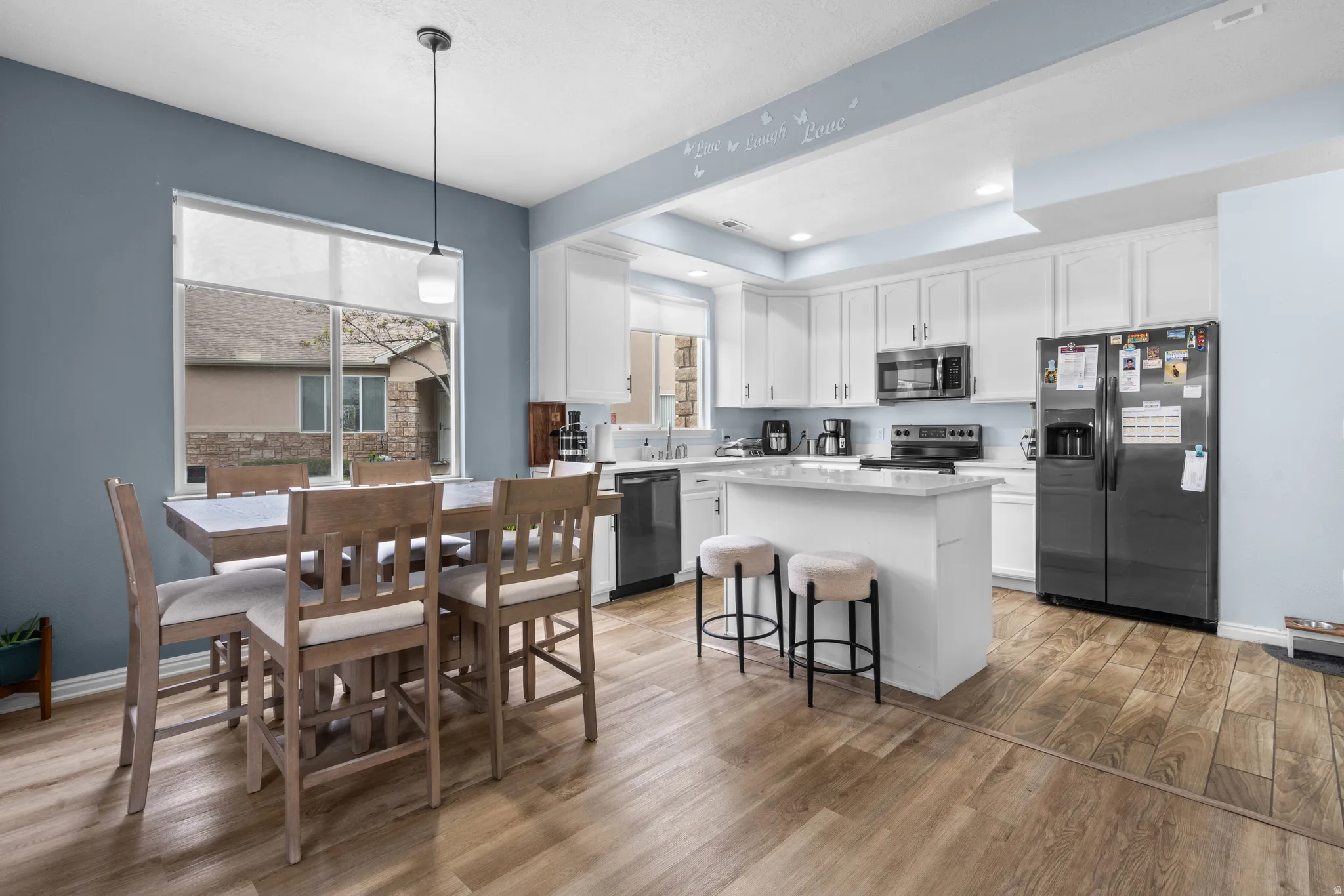 Kitchen with white cabinets, stainless steel appliances, a center island, and light wood-type flooring