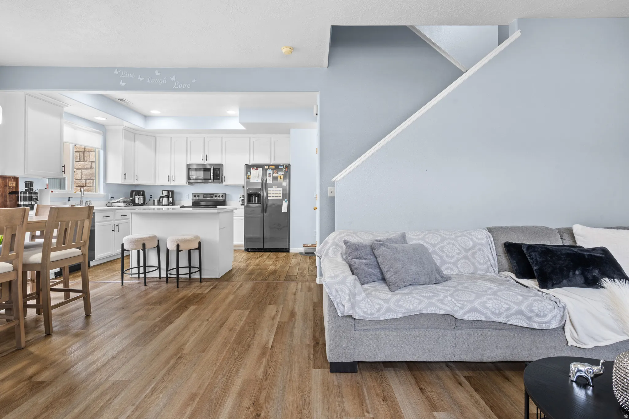 Living room with light wood-style flooring, recessed lighting, and a raised ceiling