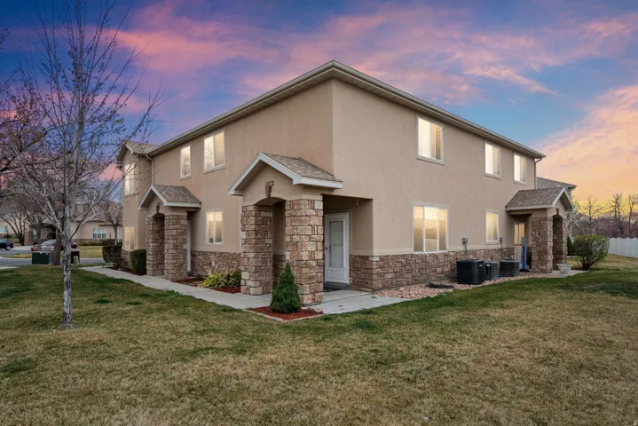 Traditional home with stucco siding, stone siding, a front lawn, and a shingled roof