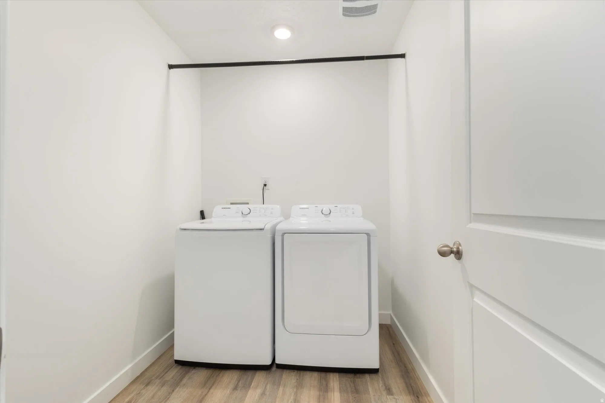Laundry area with light wood-type flooring and washing machine and clothes dryer
