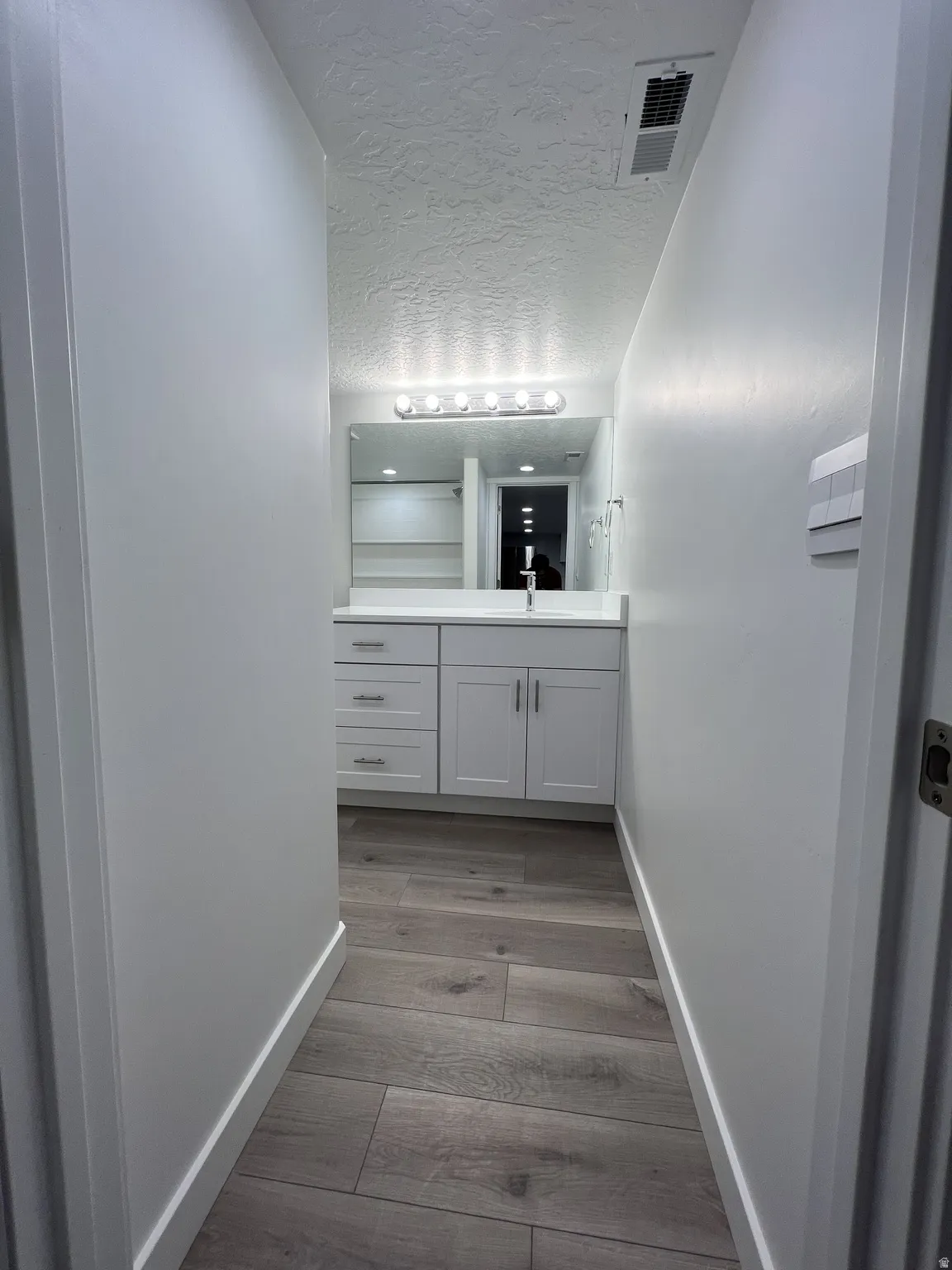 Bathroom with vanity, light wood finished floors, and a textured ceiling