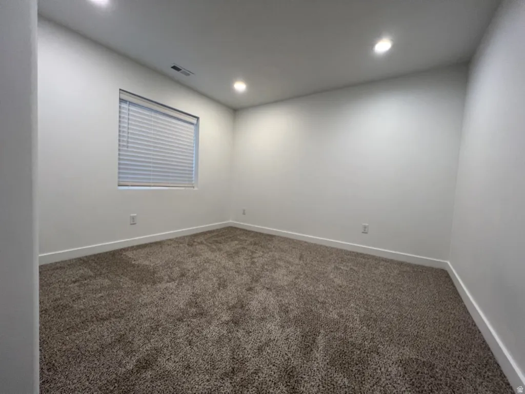 Empty room with dark carpet and recessed lighting