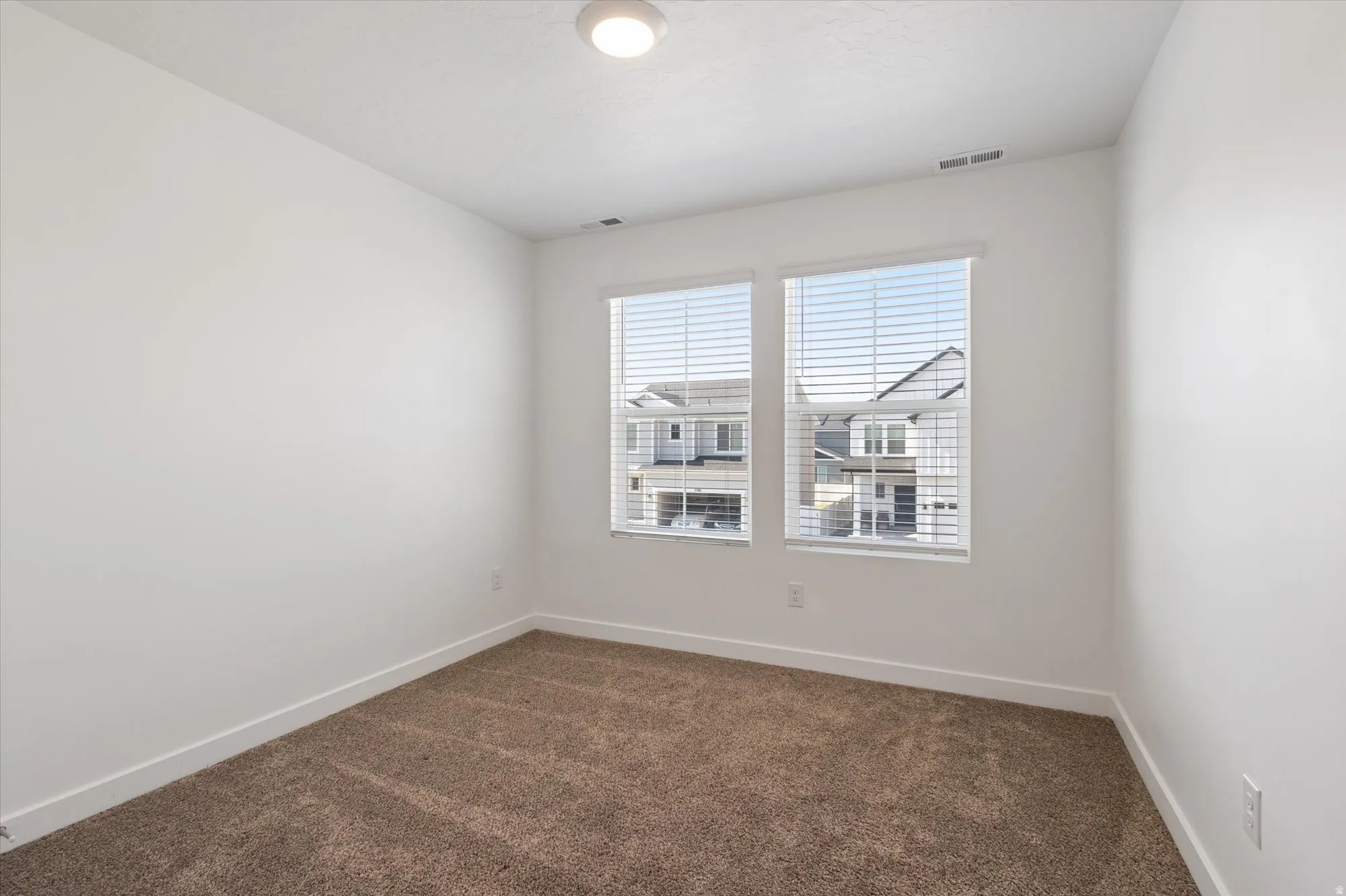 Empty room with dark colored carpet and baseboards