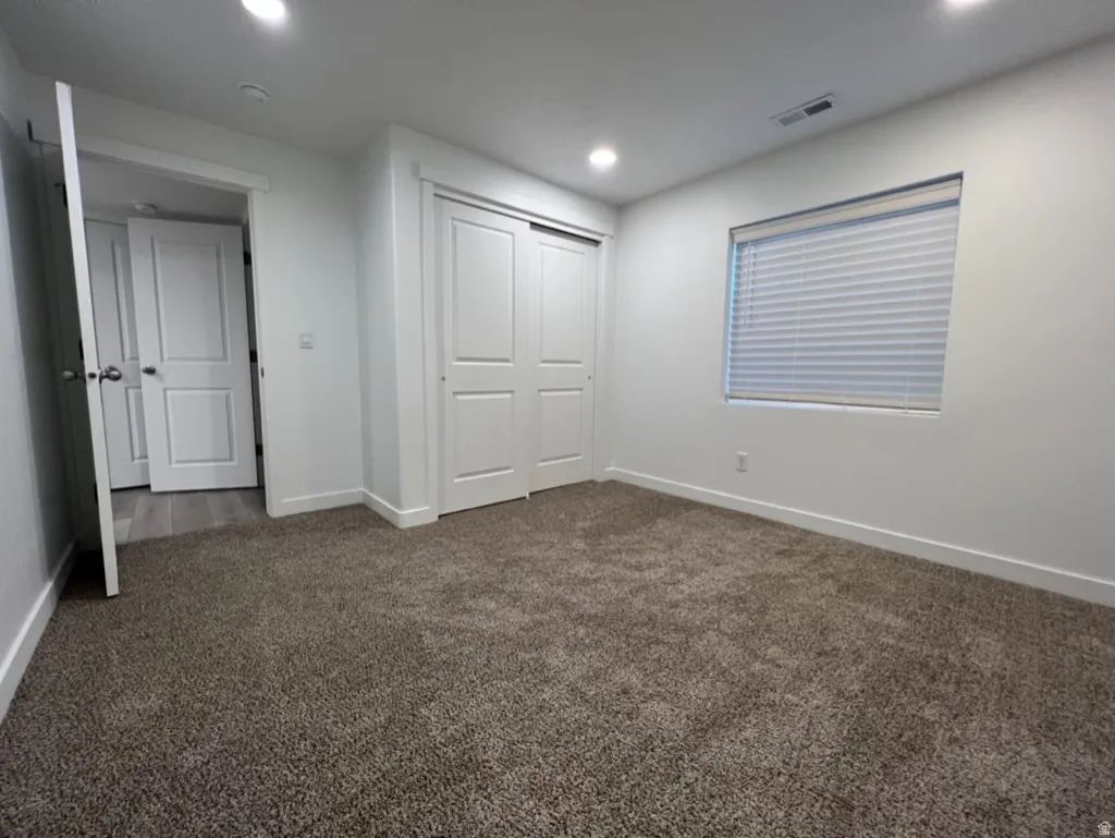 Unfurnished bedroom with dark carpet, a closet, and recessed lighting