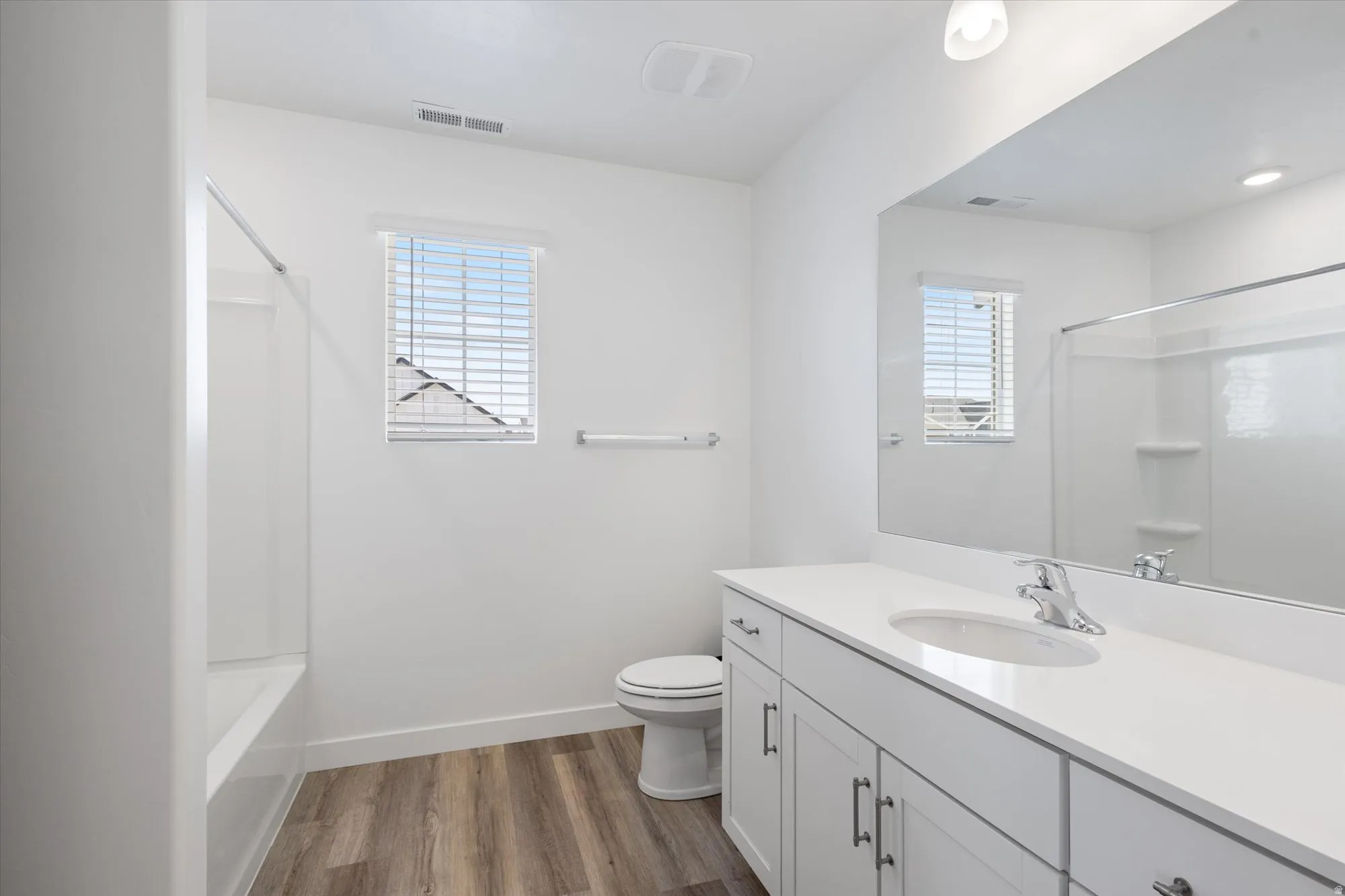 Full bath with vanity, dark wood finished floors, plenty of natural light, and shower / bath combination