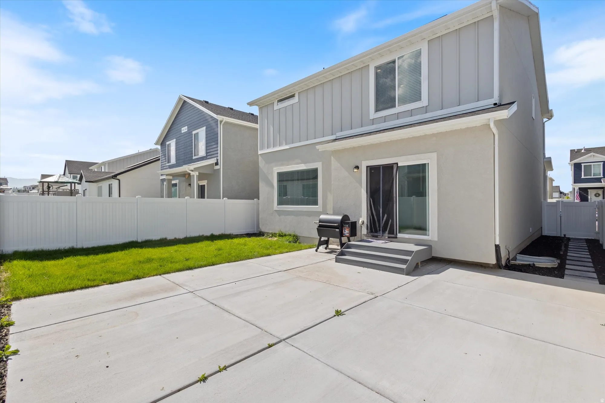 Rear view of house featuring a patio area, a fenced backyard, board and batten siding, and stucco siding