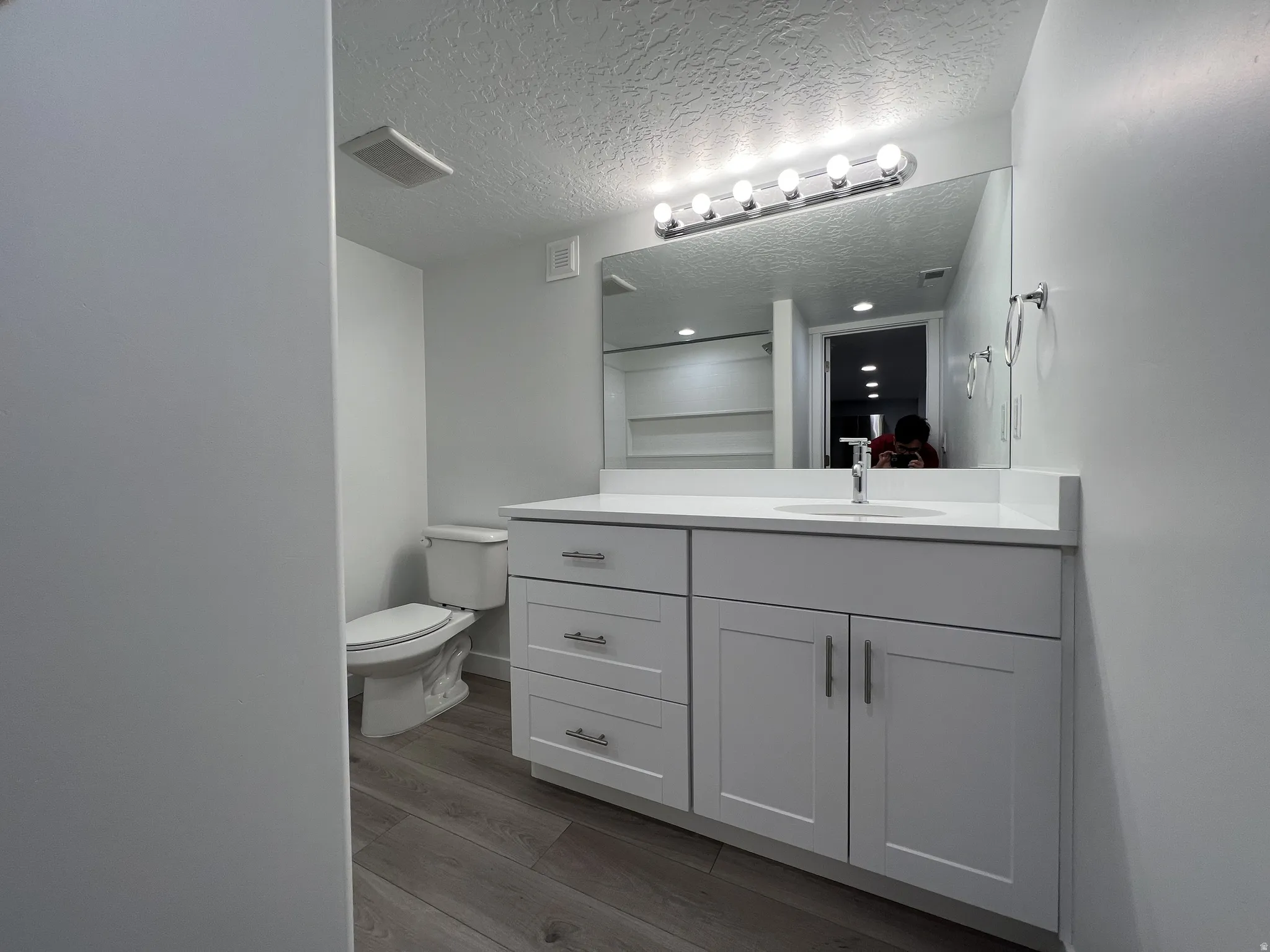 Bathroom featuring dark wood-style flooring, vanity, and a textured ceiling