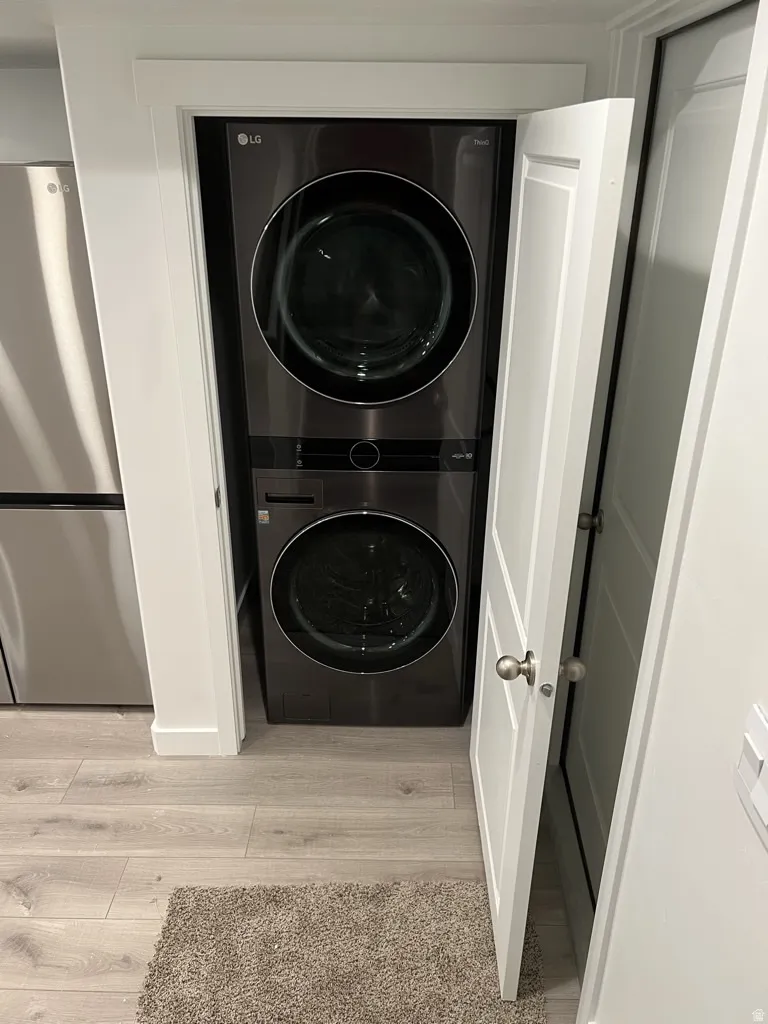 Laundry area featuring light wood-type flooring and stacked washer and clothes dryer