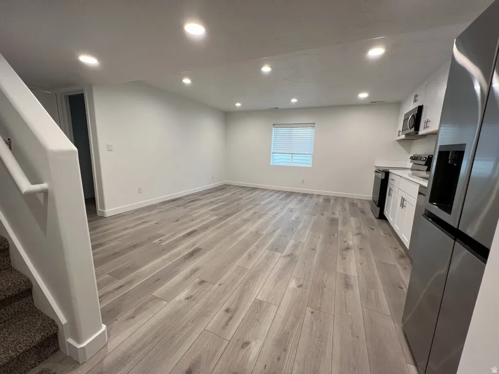 Kitchen featuring white cabinetry, stainless steel appliances, light wood-type flooring, recessed lighting, and open floor plan