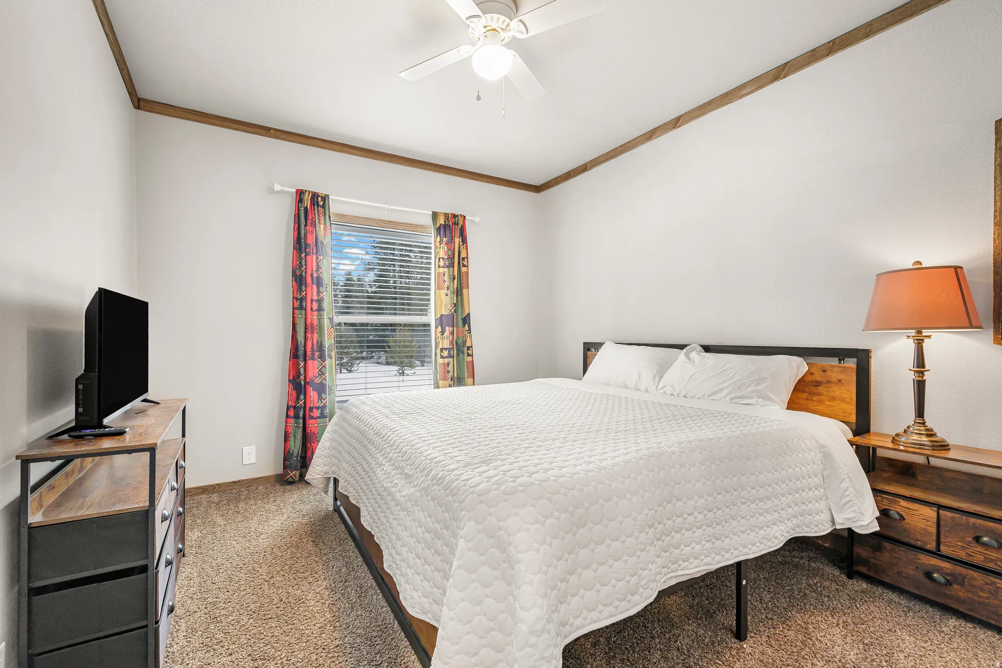 Carpeted bedroom featuring ceiling fan and ornamental molding