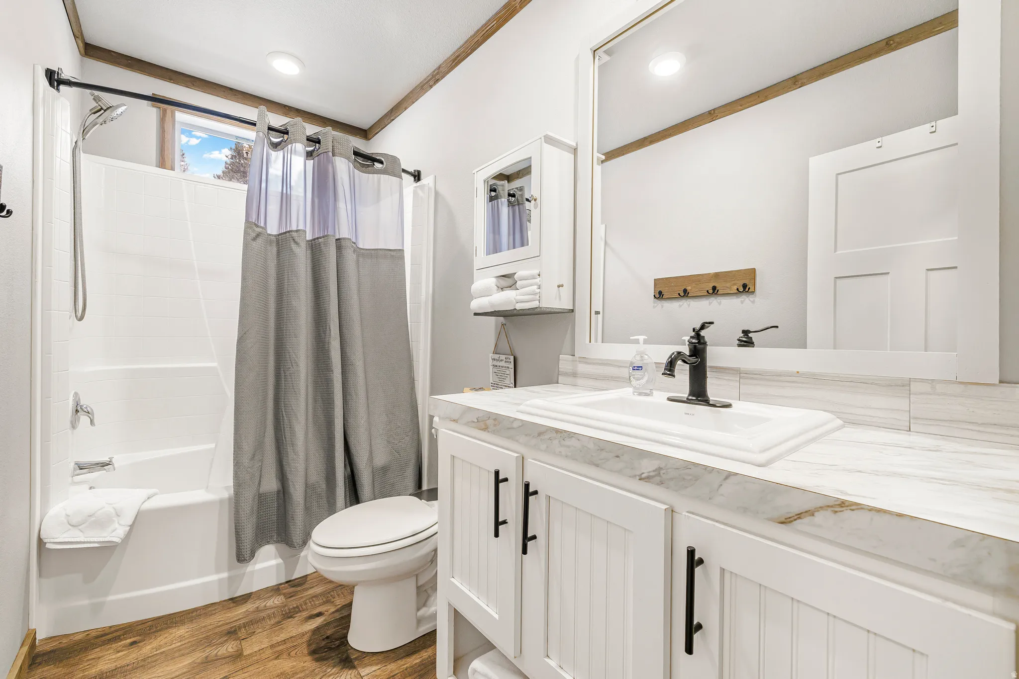 Bathroom with vanity, shower / bath combo, dark wood-type flooring, and crown molding