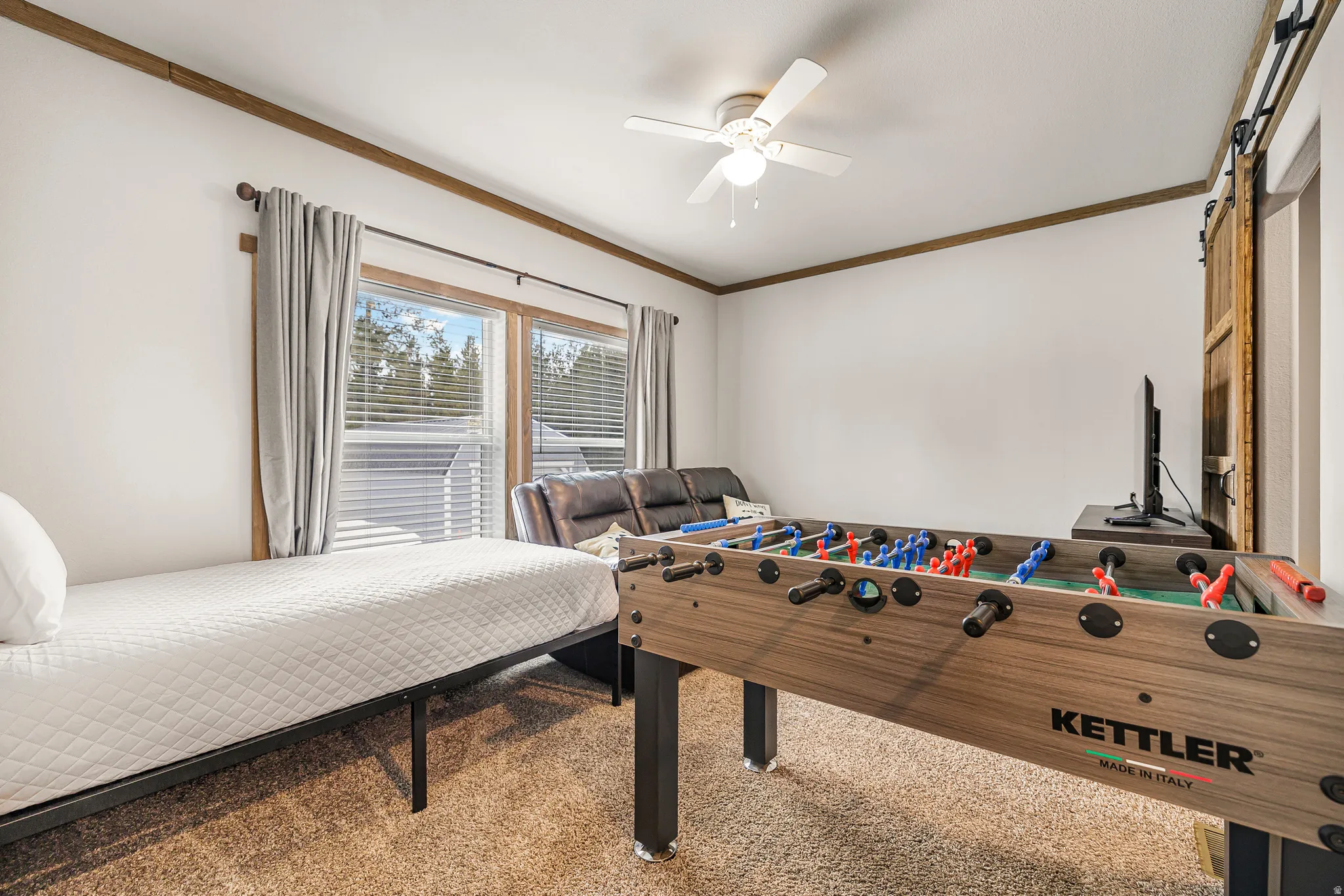 Bedroom with a barn door, crown molding, carpet flooring, and ceiling fan