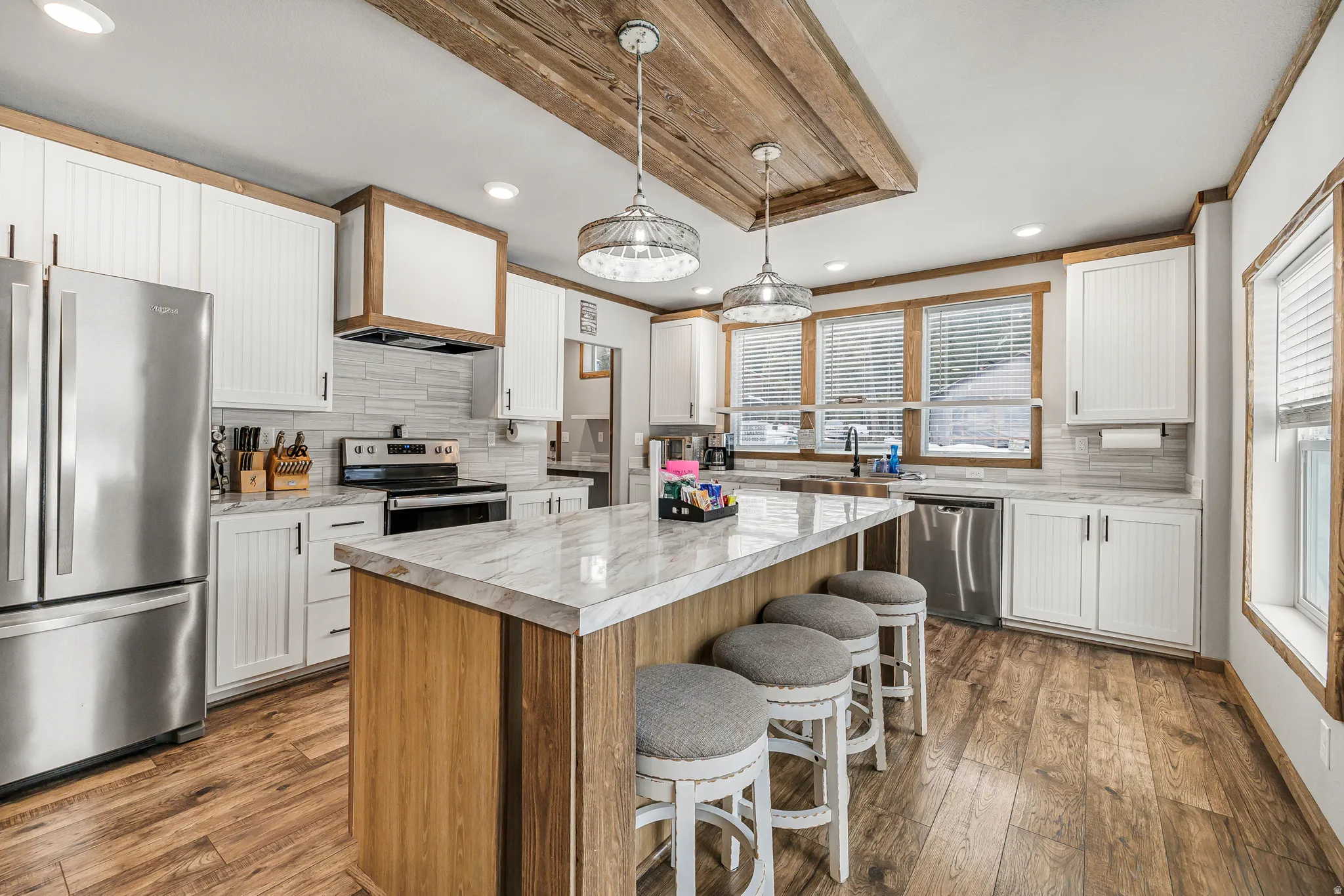 Kitchen featuring stainless steel appliances, two tone cabinets, a breakfast bar area, decorative backsplash, and a kitchen island