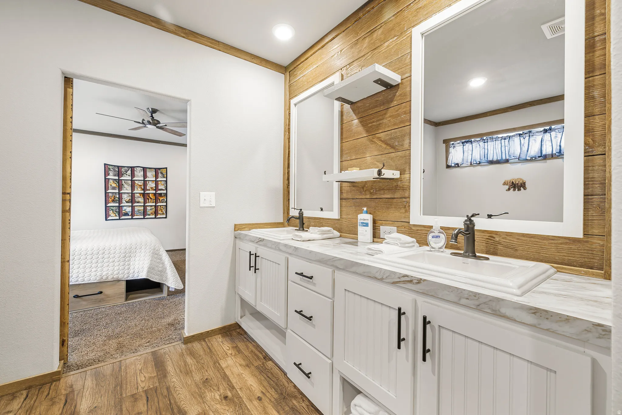 Ensuite bathroom with crown molding, double vanity, plenty of natural light, and light wood finished floors