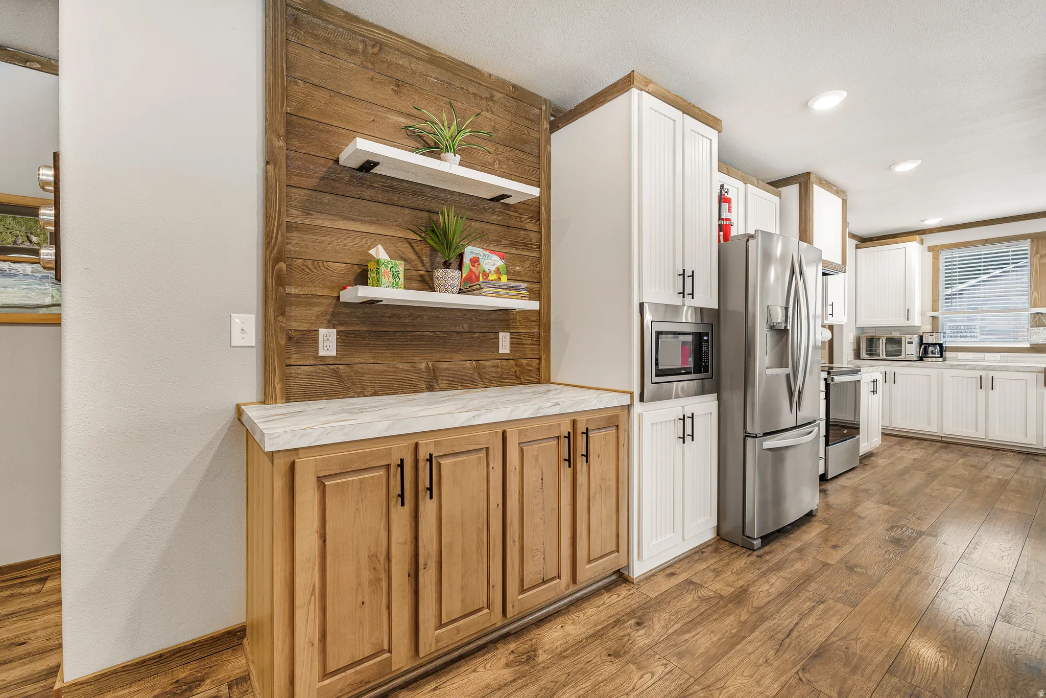 Kitchen with light wood-style flooring, stainless steel appliances, open shelves, recessed lighting, and white cabinetry