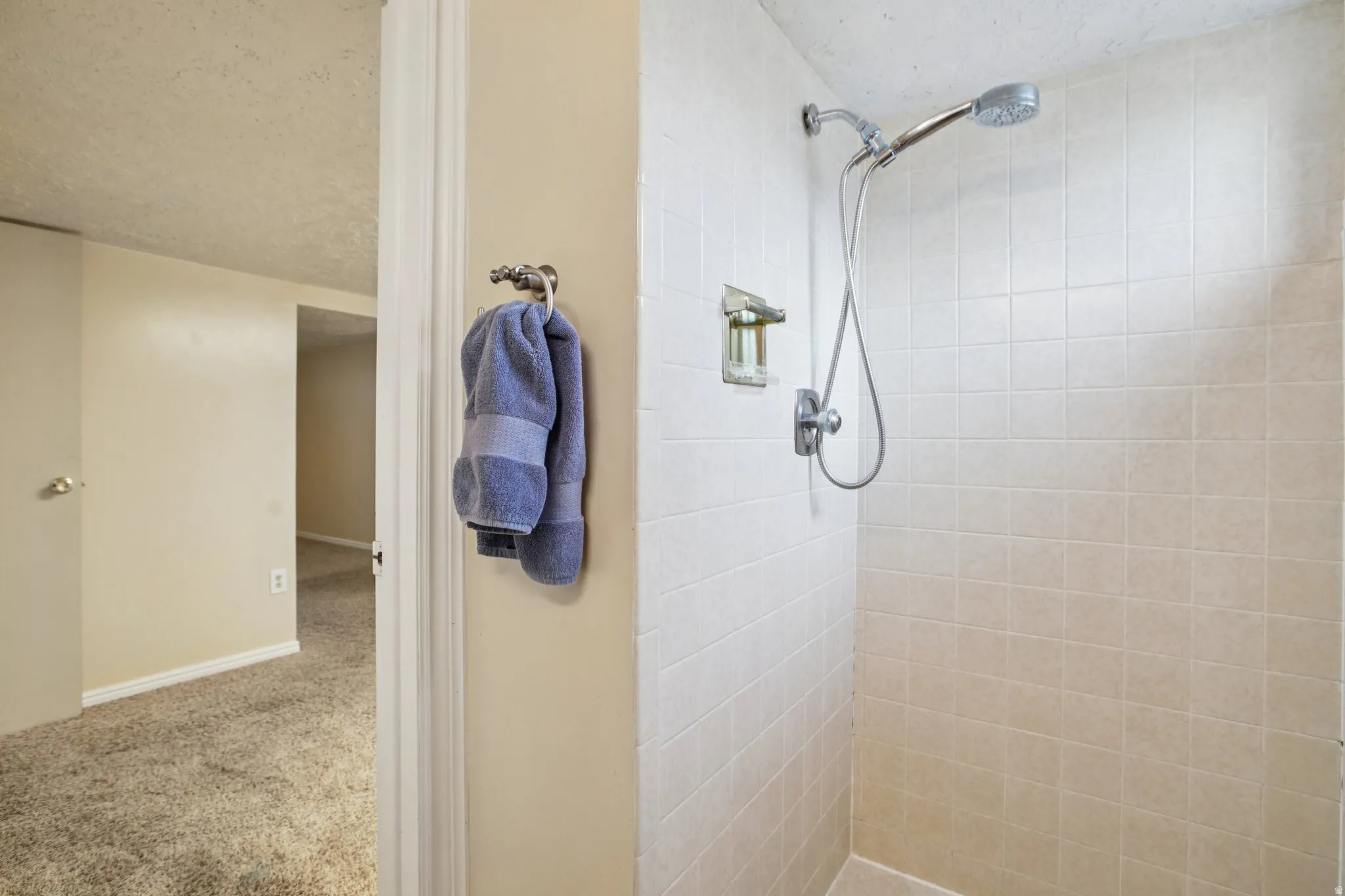 Bathroom with a textured ceiling, a stall shower, and carpet floors