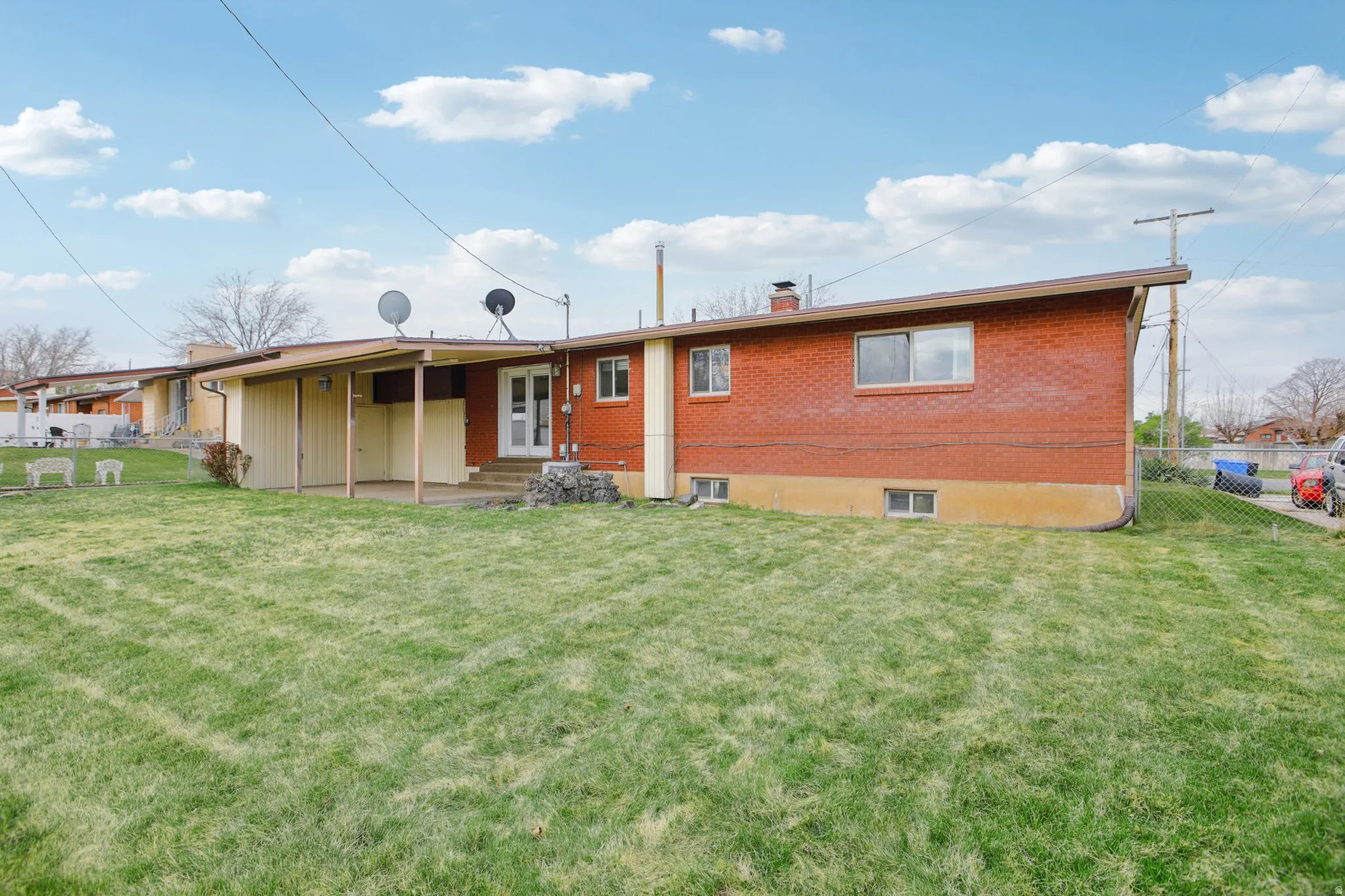 Rear view of house featuring brick siding, a chimney, and a patio area