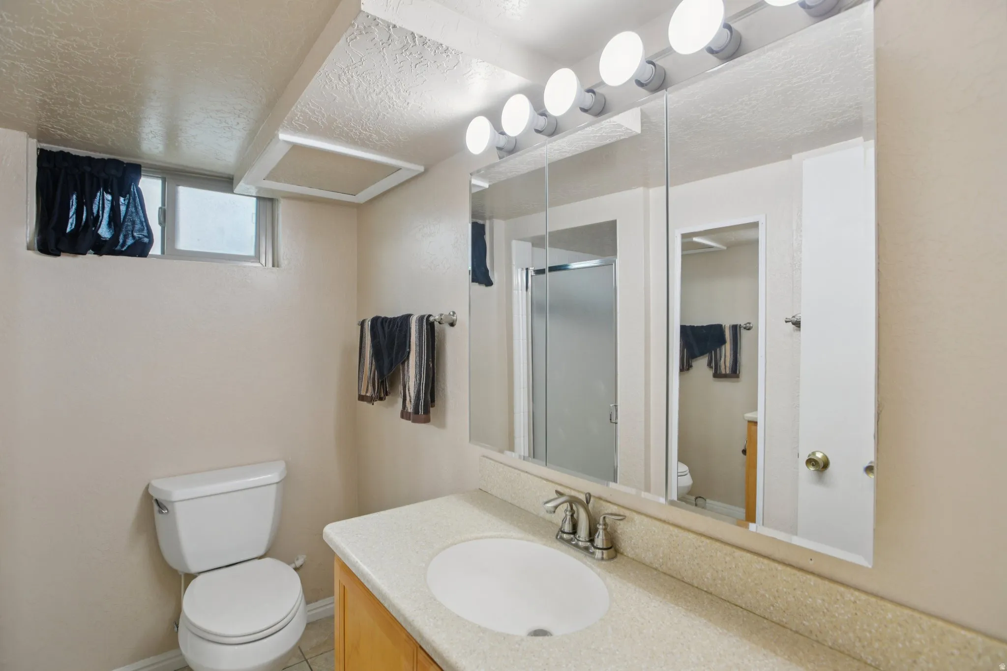 Full bath featuring vanity, a shower stall, and a textured ceiling