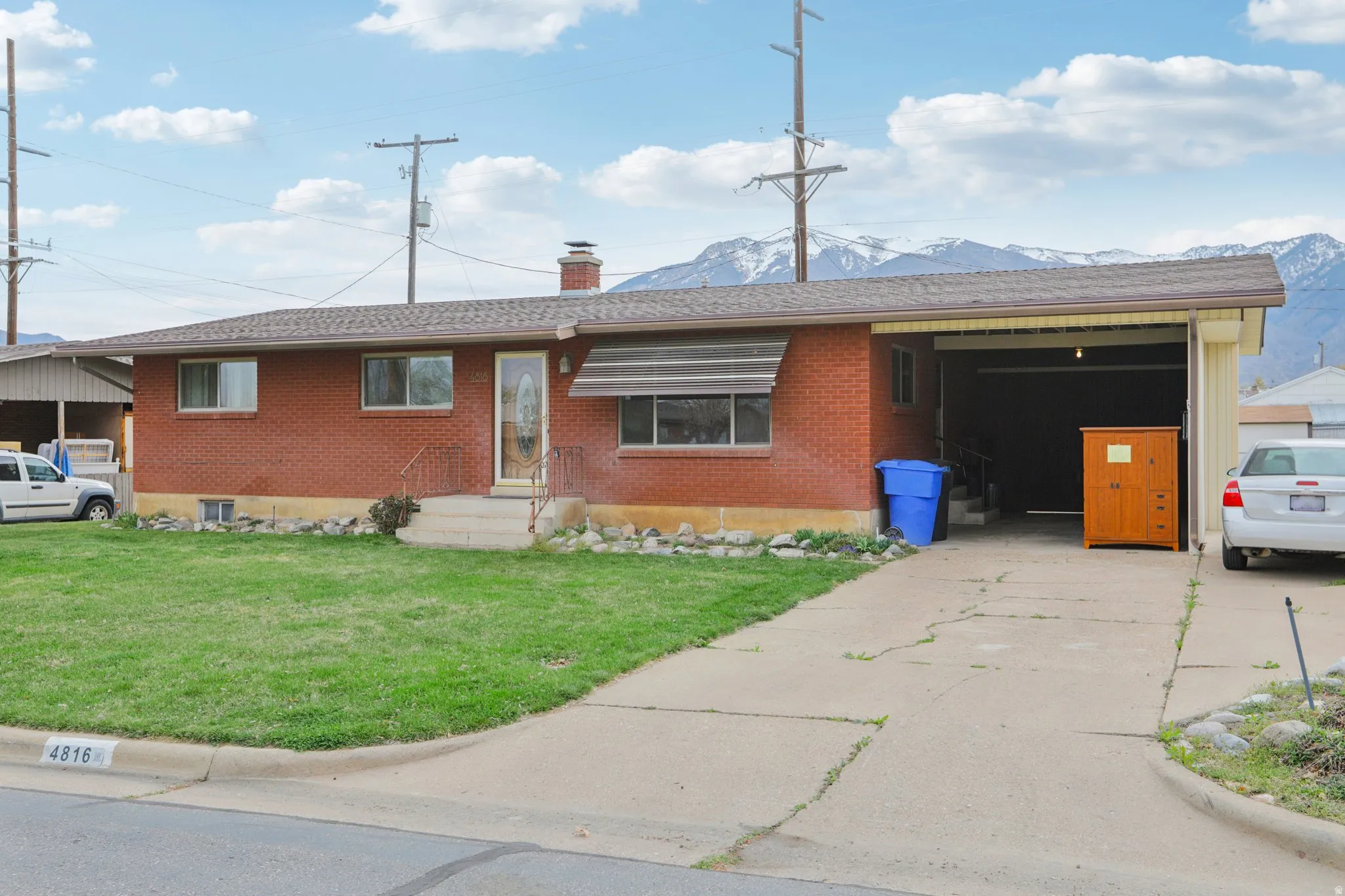 Ranch-style home featuring a front yard, brick siding, a chimney, and concrete driveway