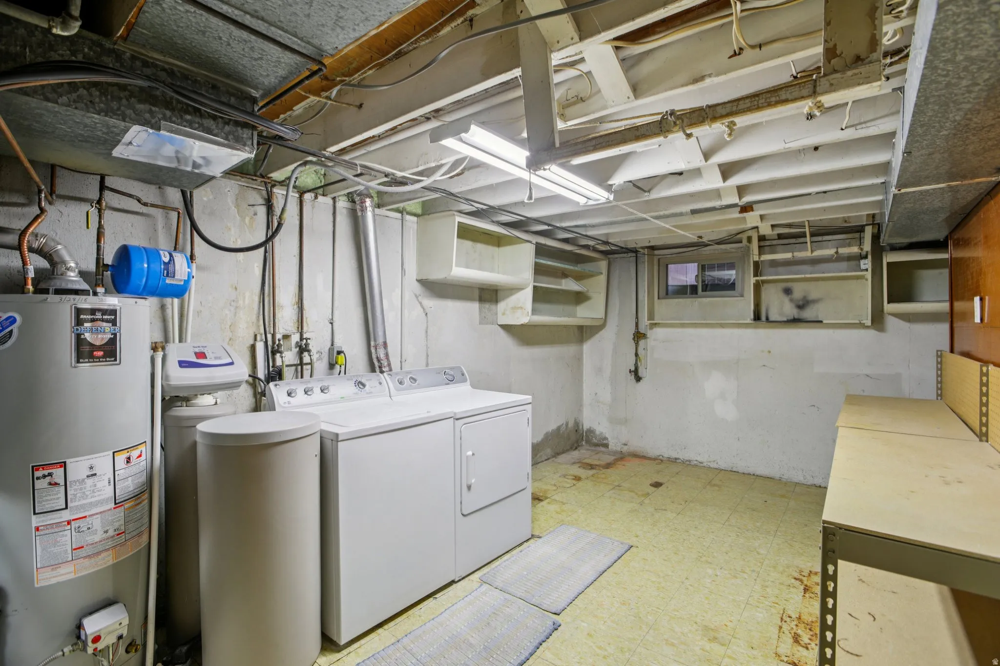 Laundry area with light flooring, water heater, and washer and dryer