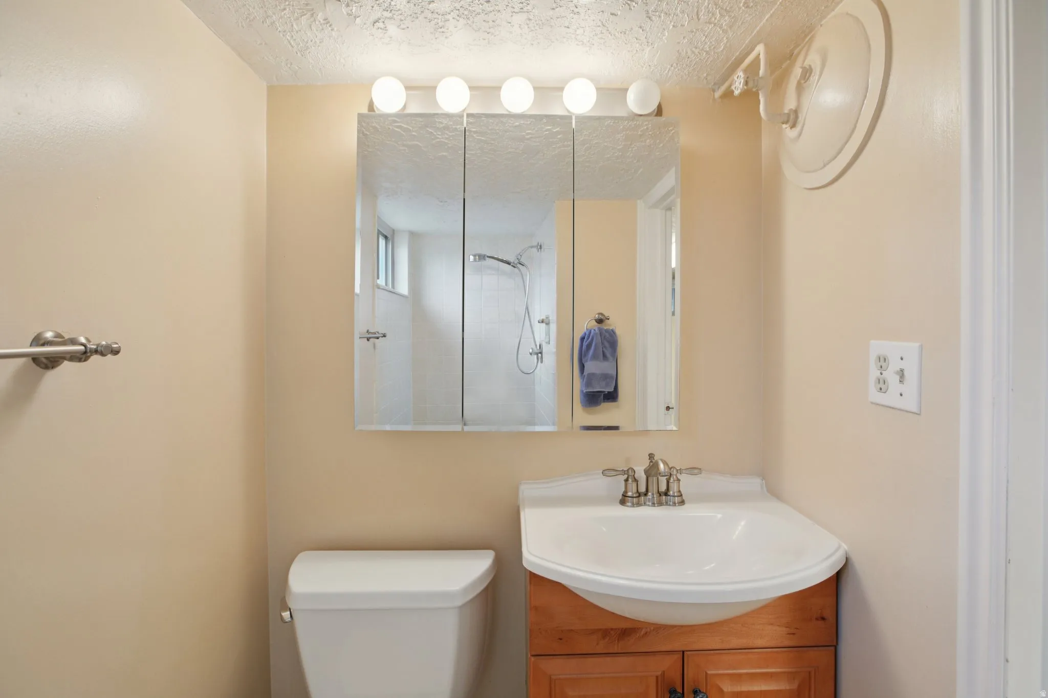 Bathroom featuring vanity, a tile shower, and a textured ceiling