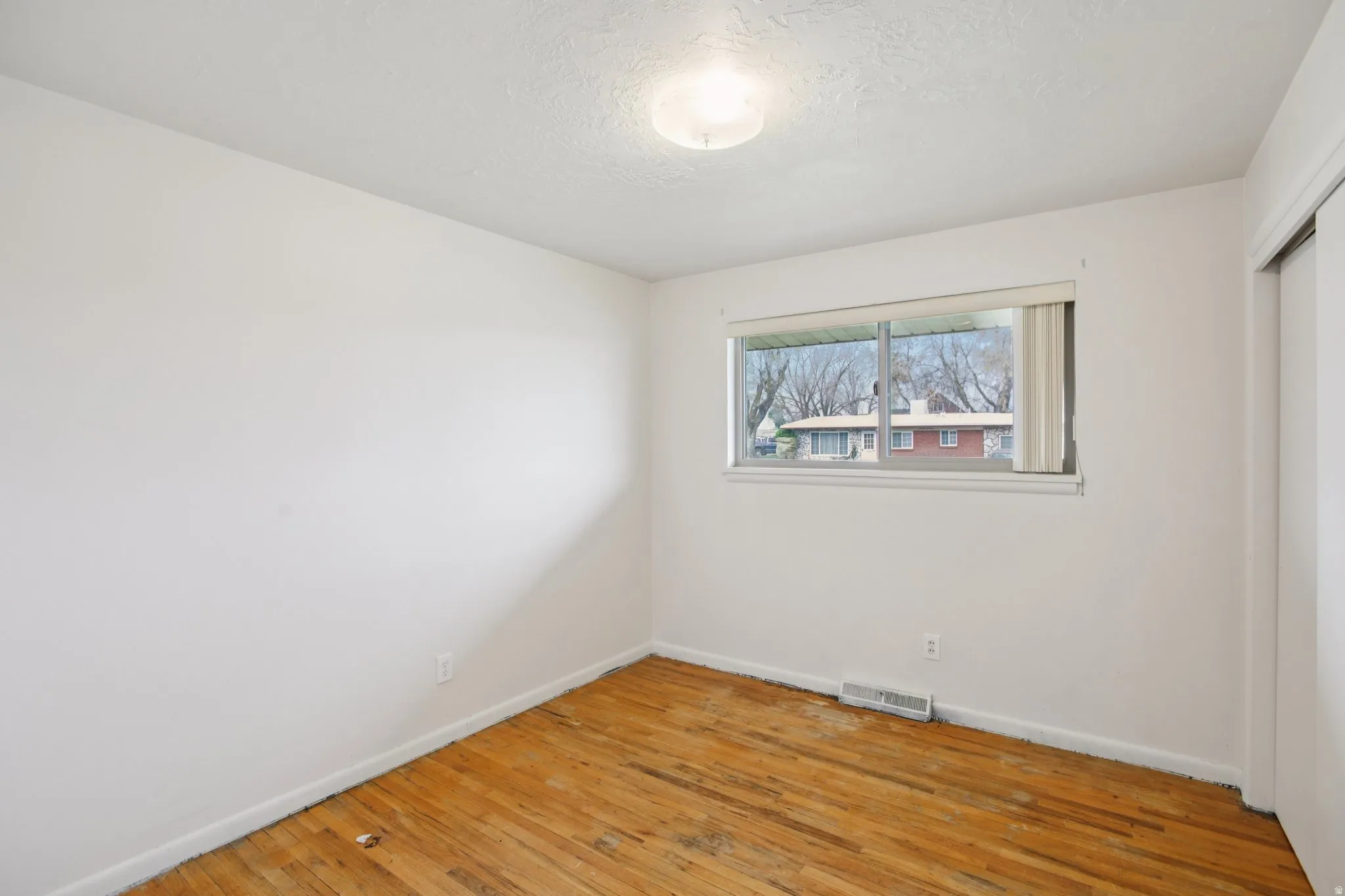 Unfurnished bedroom featuring light wood-type flooring, a closet, and a textured ceiling