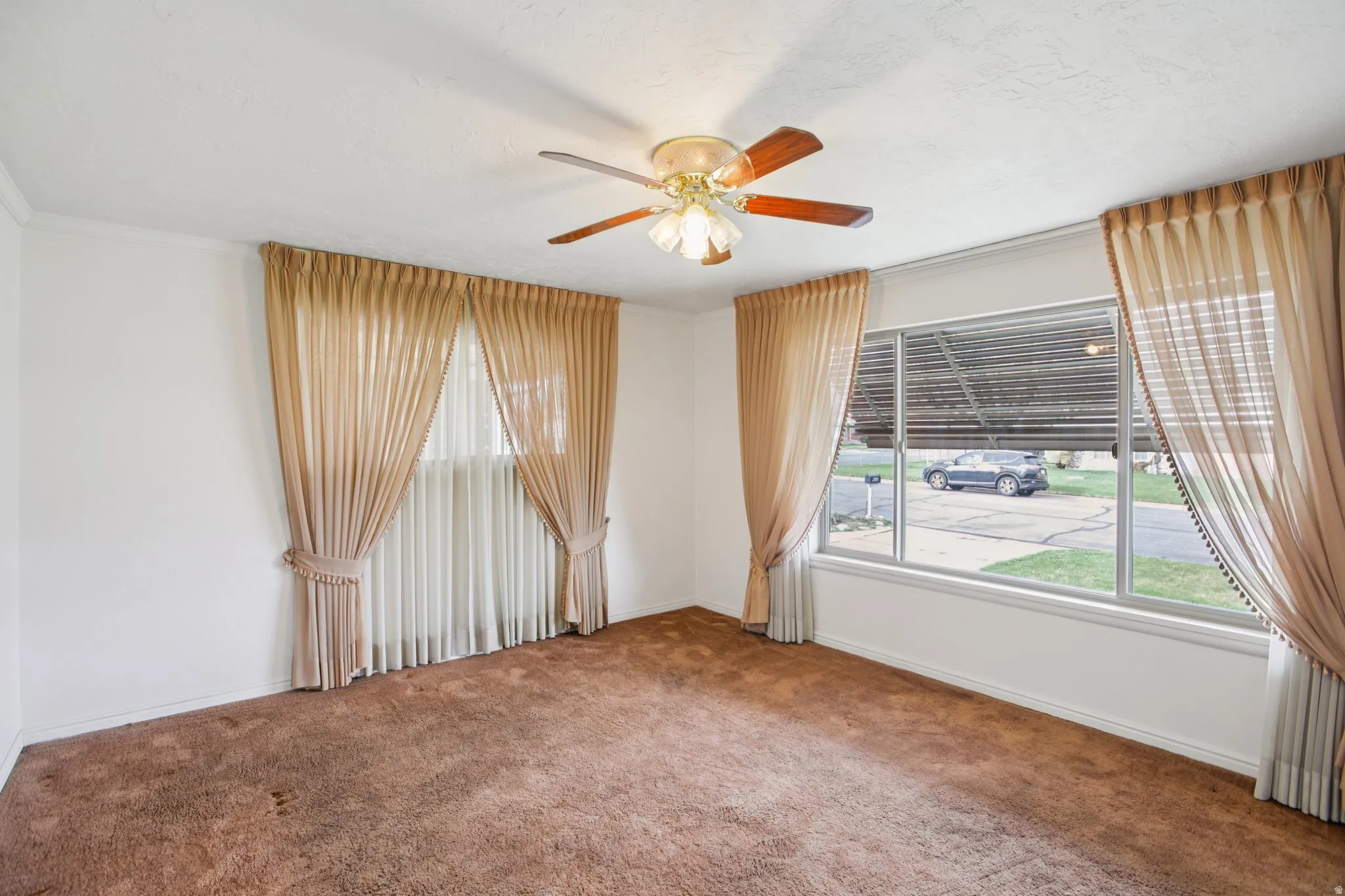 Carpeted spare room with a ceiling fan and baseboards